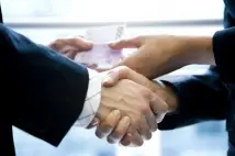 two people handshaking exchanging gift. The Bribery Act 2010: are you running a risk of breaking the law?