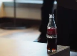 glass bottle of coca cola on a table edge - A Recipe for Success | How do you Protect Know-How?