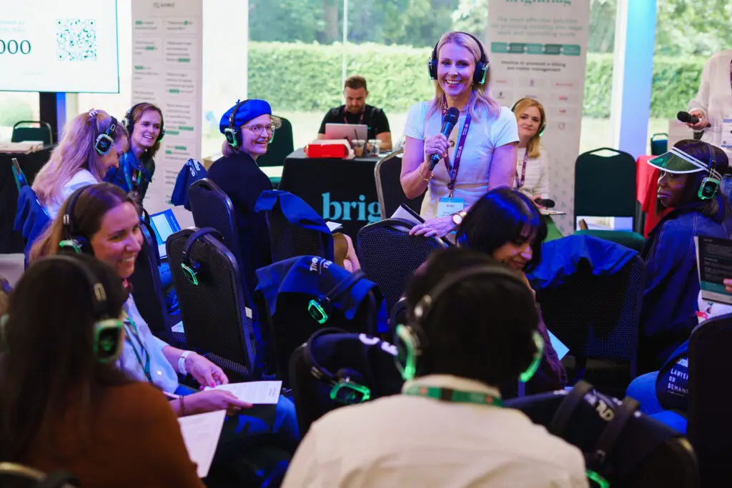 Sarah is on the microphone. Rachel is behind acting as the GC and the rest of the attendees have silent disco headphones on.